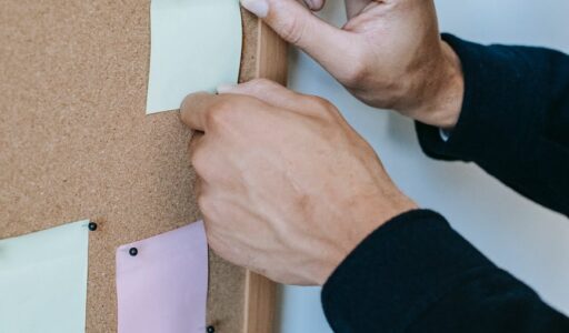 faceless man pinning memo papers on noticeboard