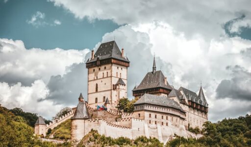 white and black concrete castle on mountain under white clouds